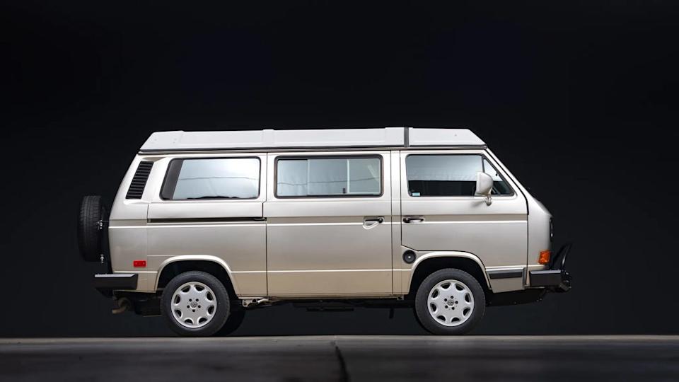side view of beige van with sliding door and white roof against black background.