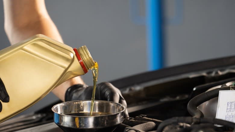 Motor oil is being poured into a car's engine