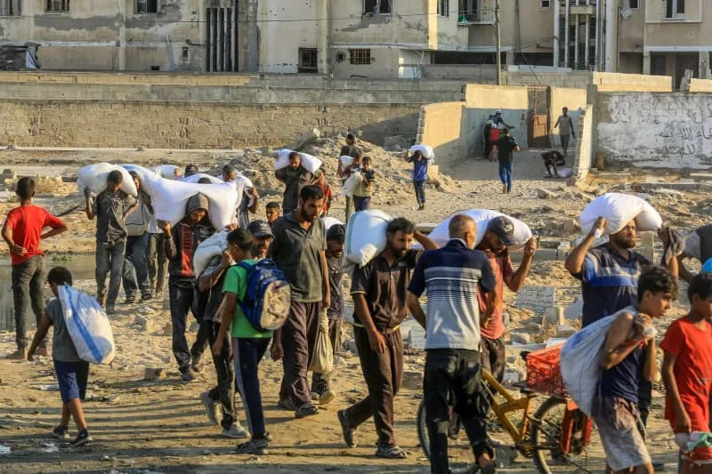 Palestinians carrying bags of flour walk along a street in Khan Yunis after trucks carrying humanitarian aid entered the southern Gaza Strip through the Israeli-controlled Kerem Shalom border crossing. Abed Rahim Khatib/dpa