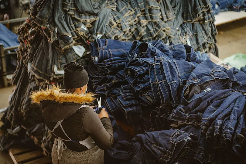 A worker inspects finished jeans at the Afri-Expo Textiles Ltd. denim factory in Maseru, Lesotho. / Credit: Fredrik Lerneryd/Bloomberg via Getty Images