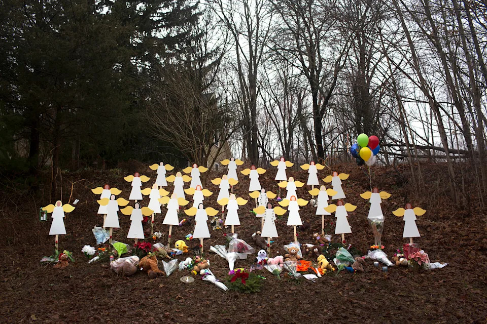 Twenty-seven wooden angel figures along a road with bouquets of flowers surrounding them (Lisa Wiltse / Corbis via Getty Images file)