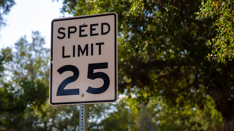 A 25-mph speed limit sign in front of green trees