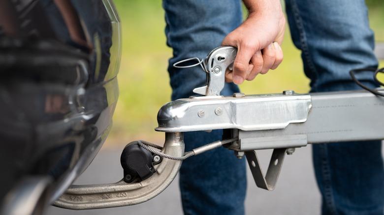 A person attaching a trailer onto a hitch.