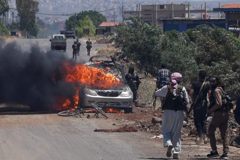 TOPSHOT - Bedouin and tribal fighters deploy as a car burns at the western entrance of Syria's Druze heartland of Sweida on July 18, 2025. Armed tribes supported by Syria's Islamist-led government clashed with Druze fighters in the community's Sweida heartland on July 18, a day after the army withdrew under Israeli bombardment and diplomatic pressure. (Photo by Bakr ALKASEM / AFP) (Photo by BAKR ALKASEM/AFP via Getty Images)