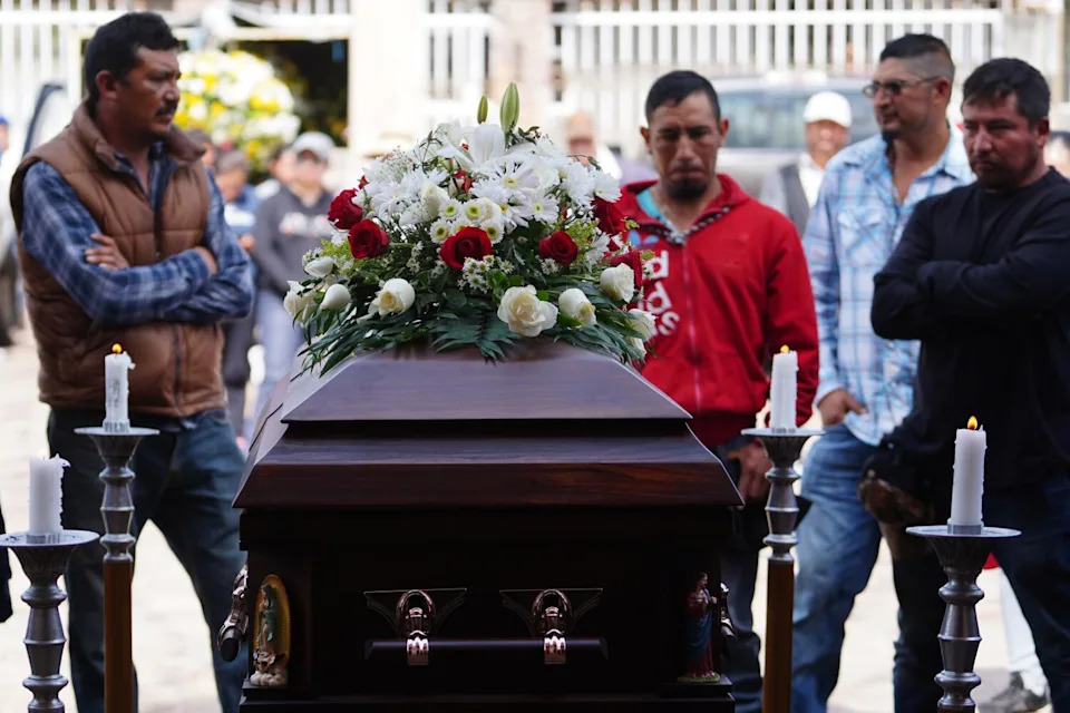 Men stand near a coffin.