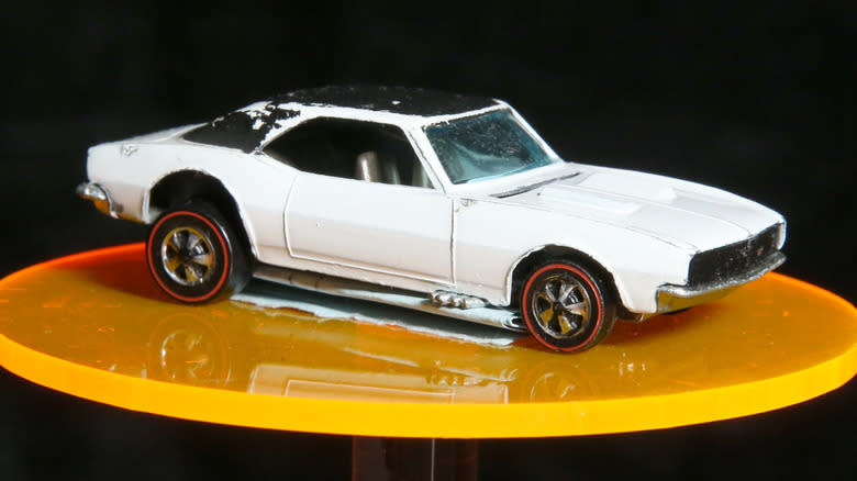 The white enamel 1968 Chevy Camaro Hot Wheels from Hong Kong on a yellow circular display.