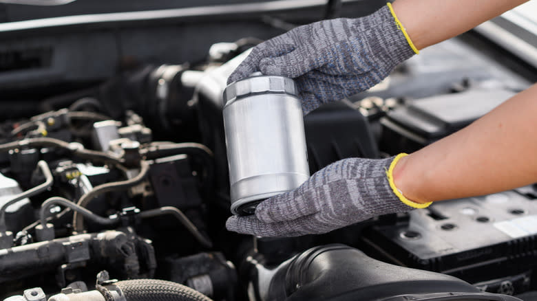 A mechanic holding a diesel fuel filter