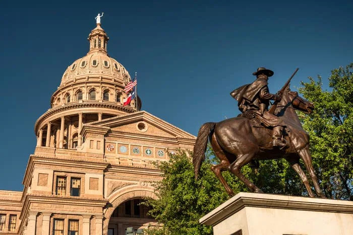 Texas Capitol building with a prominent statue of a mounted figure in the foreground