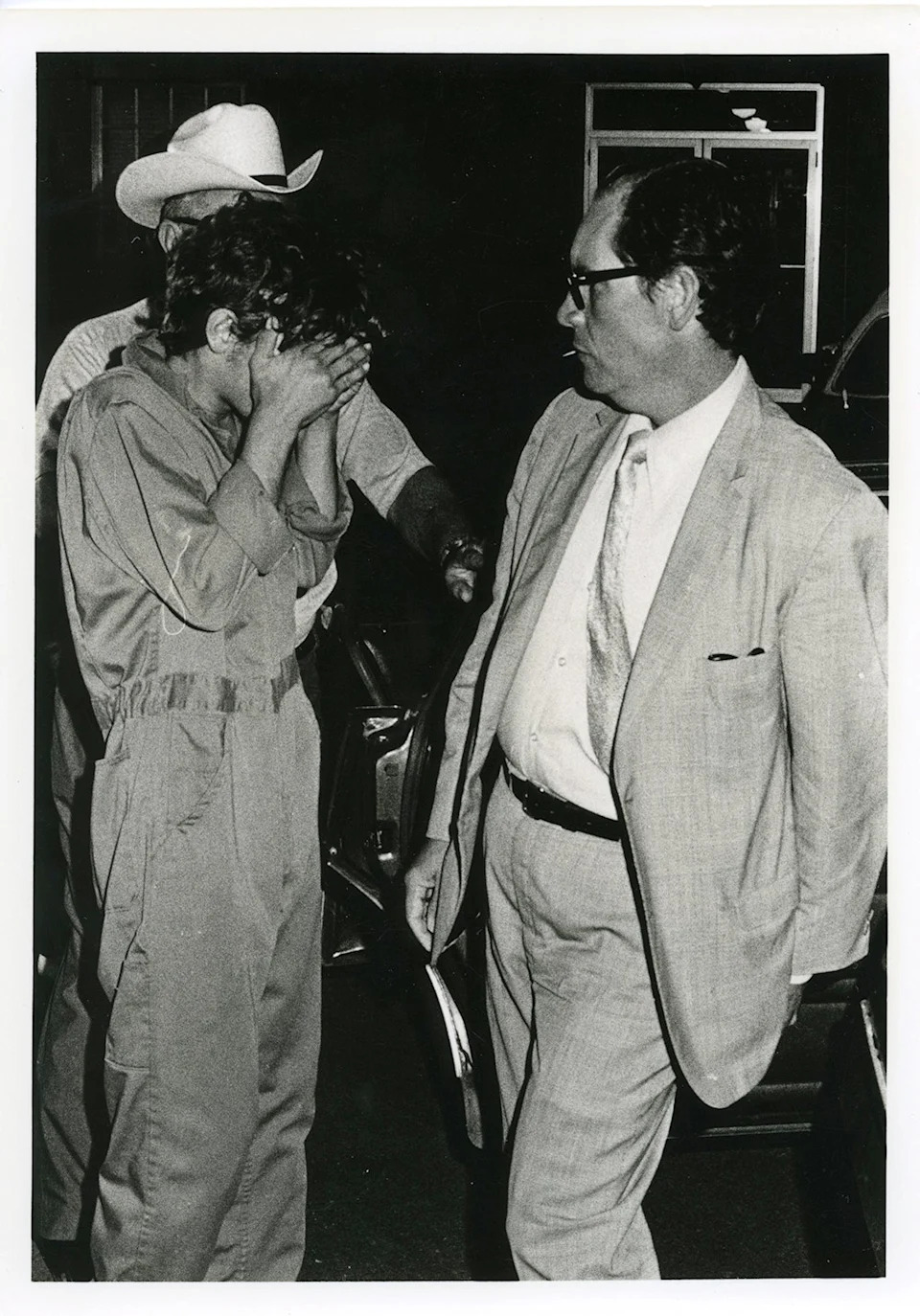 Elmer Wayne Henley Jr. covering his face while being arrested.