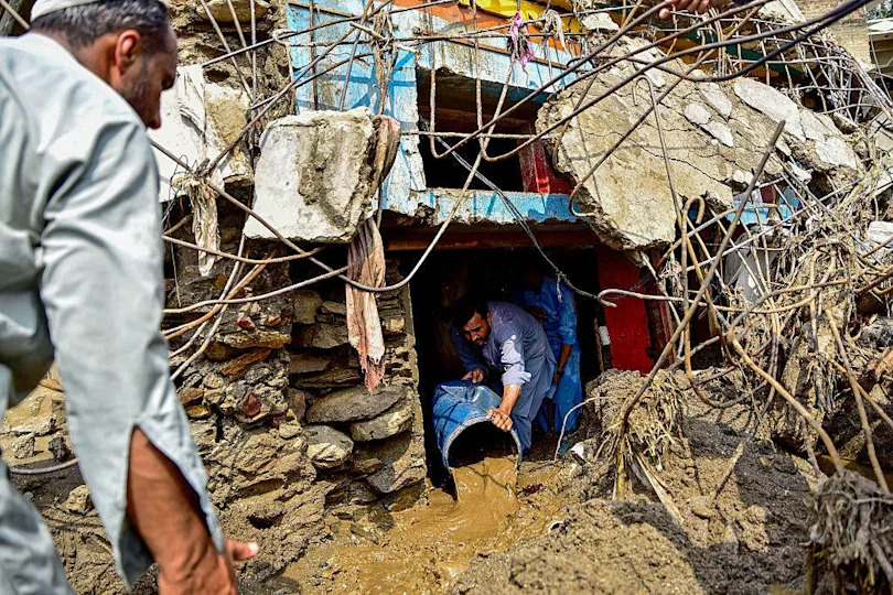 A resident removes sludge from his damaged house a day after flash floods in the Buner district of the monsoon-hit northern Pakistan's mountainous Khyber Pakhtunkhwa province. / Credit: HASHAM AHMED/AFP via Getty Images
