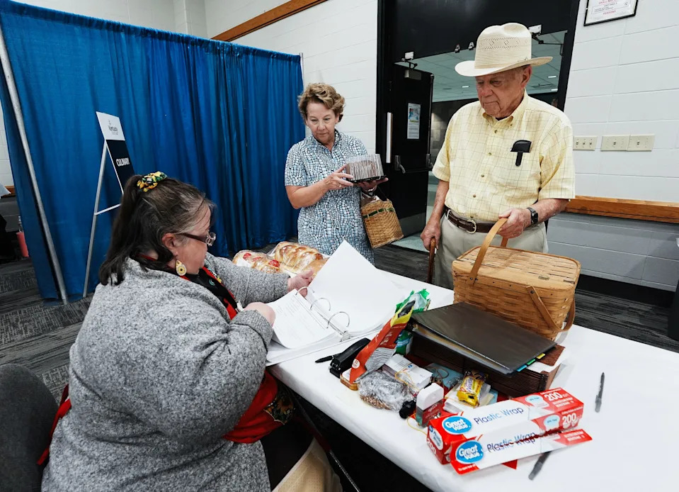Bob Hall, 95, right, and his daughter Julia Hall drop off his entries of an apple pie and a pound cake with Pam Ezell, left, to enter into the culinary contest at the Kentucky State Fairgrounds in Louisville, Ky. on Aug. 11, 2025.