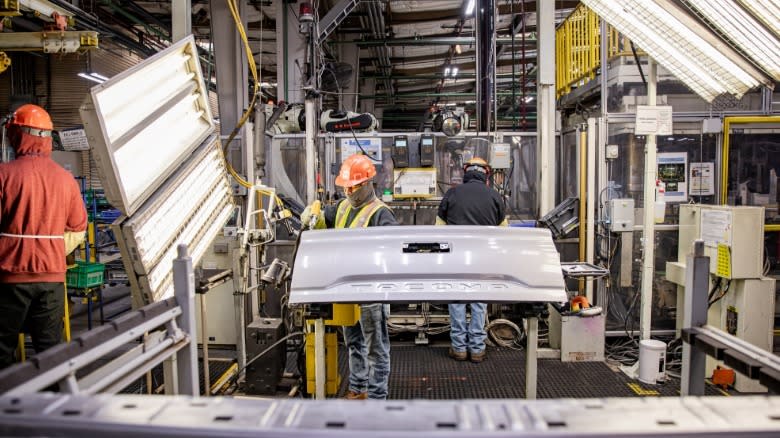 A current image from inside the Toyota Auto Body facility showing a Tacoma tailgate being inspected