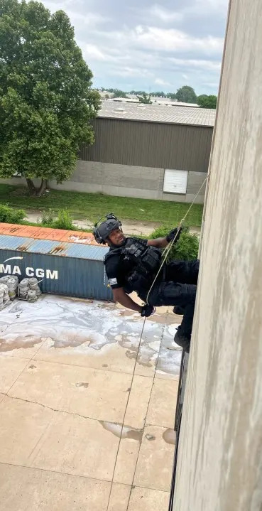 SWAT officer hanging from ropes during training