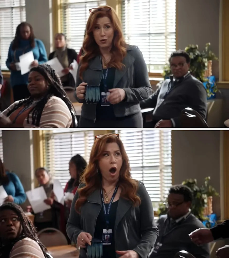 A surprised woman with long hair and a lanyard stands in an office setting among colleagues