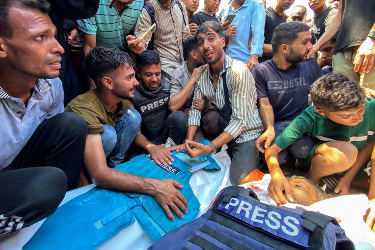 La gente llora los cuerpos de los periodistas palestinos Moaz Abu Taha (izq.) y el fotoperiodista Hussam al-Masri, periodista de Reuters, (der.), quienes murieron en un ataque israelí contra el hospital Nasser en Khan Younis, al sur de la Franja de Gaza, antes de su funeral el 25 de agosto de 2025.