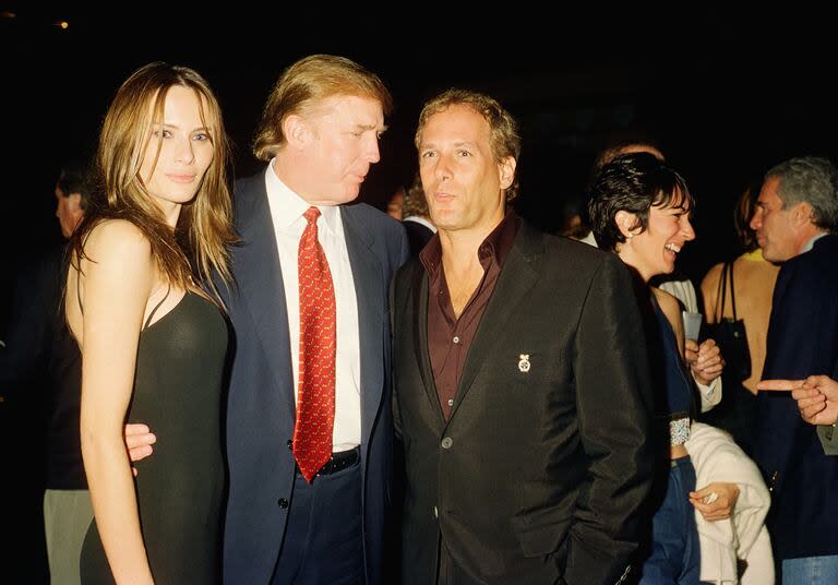 Vista de la exmodelo Melania Knauss (luego Trump) y su novio (y futuro esposo), Donald Trump (al centro), posando con el músico Michael Bolton en el club Mar-a-Lago, Palm Beach, Florida, el 12 de febrero de 2000. Entre los presentes que se ven al fondo están la socialité británica Ghislaine Maxwell y el financista estadounidense Jeffrey Epstein.
