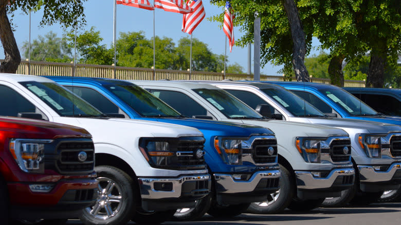 A lineup of red, white, and blue Ford F-150 pickup trucks at an Arizona car dealer