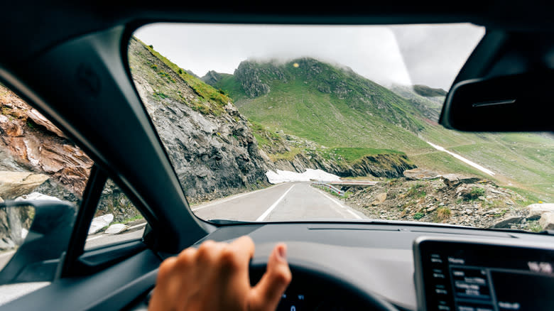 A person driving downhill on a mountain road