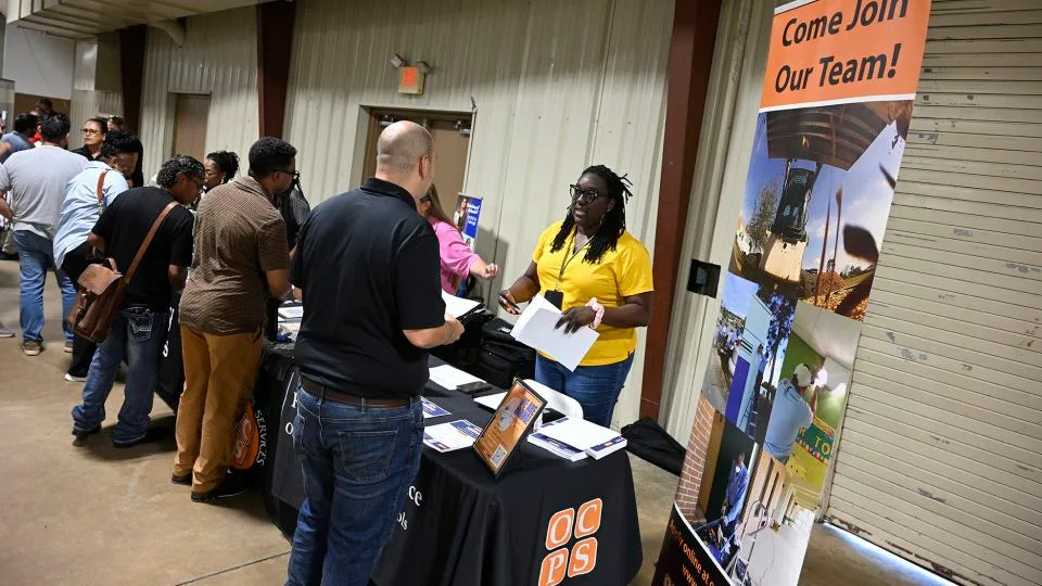 Job seekers talk with representatives from Orange County Public Schools looking to fill openings during a job fair at the Orange County Fairgrounds, on Thursday, July 10 in Orlando, Florida. - Phelan M. Ebenhack/AP