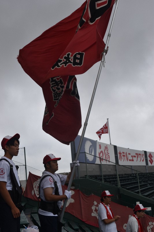 強風の中、日大山形の大きな応援団旗を掲げる松尾仁近さん＝兵庫県西宮市の阪神甲子園球場で2025年8月11日午前8時1分、中田博維撮影