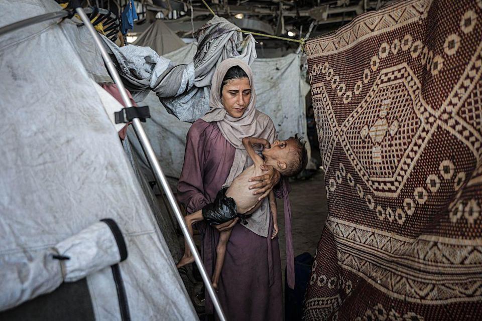 Muhammad Zakariya Ayyoub al-Matouq junto a su madre en una tienda de campaña, en Gaza.
