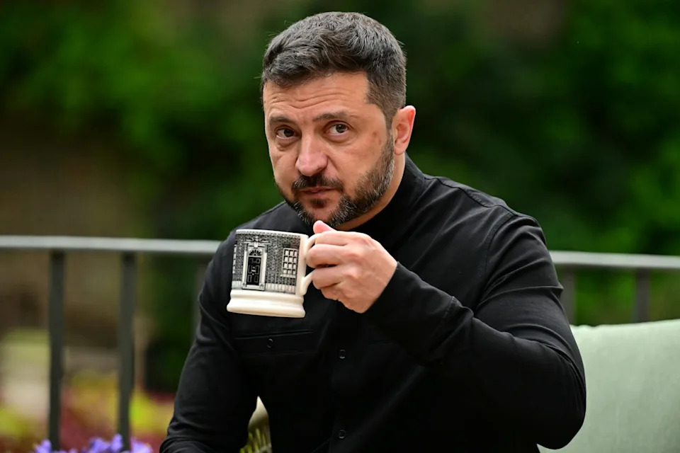 Ben Stansall/Wpa Pool via Getty Images - PHOTO: Ukraine's President Volodymyr Zelensky drinks from a Downing Street -themed mug as he sits with Britain's Prime Minister Keir Starmer in the garden of 10 Downing Street, August 14, 2025 in London.