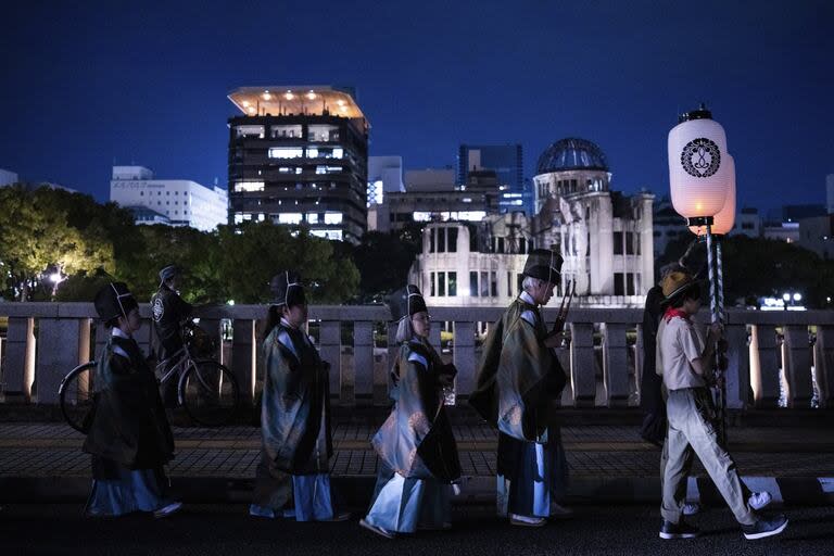 Asistentes caminan a lo largo del río Motoyasu, frente a la Cúpula de la Bomba Atómica, durante una ceremonia de conmemoración en Hiroshima, el martes 5 de agosto de 2025