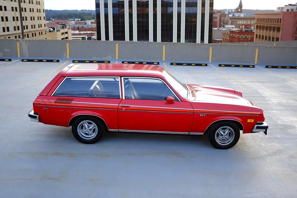 side profile view of red two door wagon with orange and yellow side stripes parked in rooftop lot.