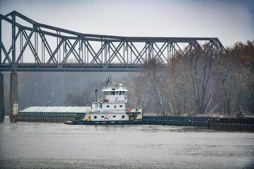 Barges float along the banks of the Illinois River near the Peoria Lock and Dam.
