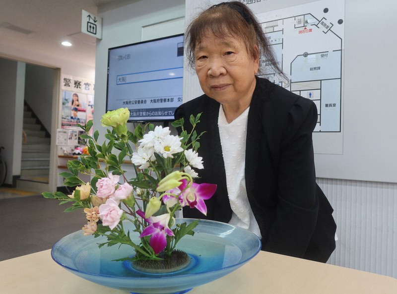 大阪府警此花署に花を届ける清水満子さん。作品には自身の大好きなカーネーションや菊が使われている＝大阪市此花区の大阪府警此花署で2025年7月28日午前11時31分、露木陽介撮影