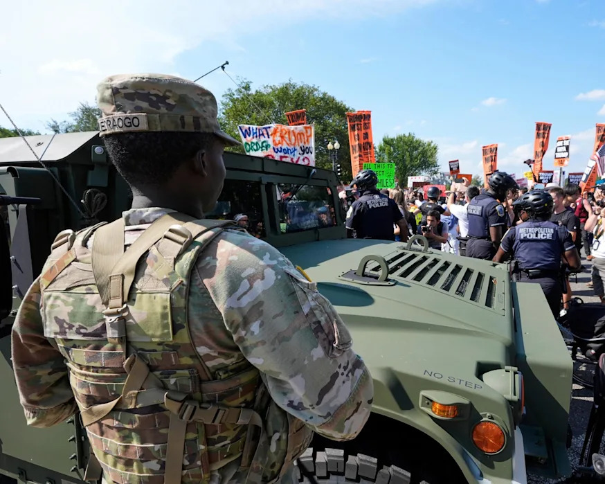 <span>Metropolitan police officers and military police soldiers look ahead in Washington DC on 16 August.</span><span>Photograph: Alex Brandon/AP</span>