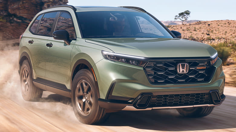 A green 2026 Honda CR-V TrailSport driving down a dirt road