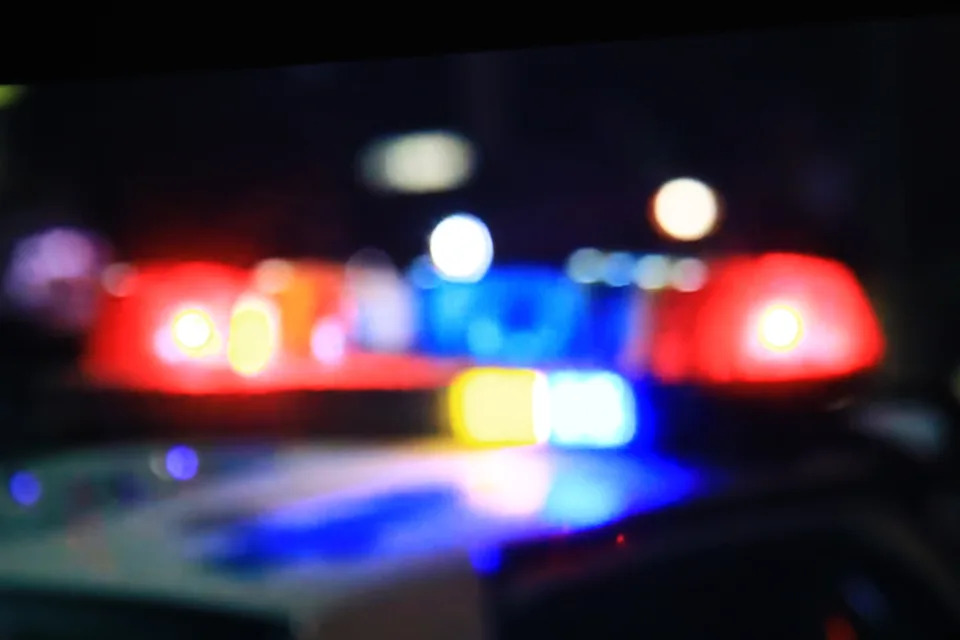 Blurred police car lights with red and blue sirens in the foreground, creating an abstract, bokeh effect