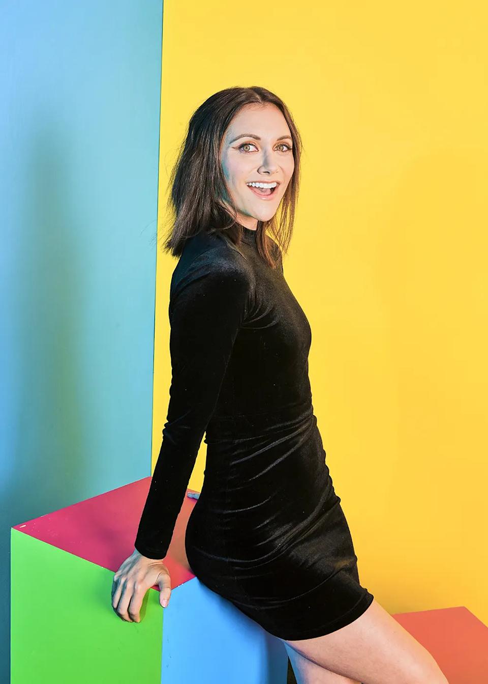 Alyson Stoner con un vestido corto de terciopelo negro de manga larga.