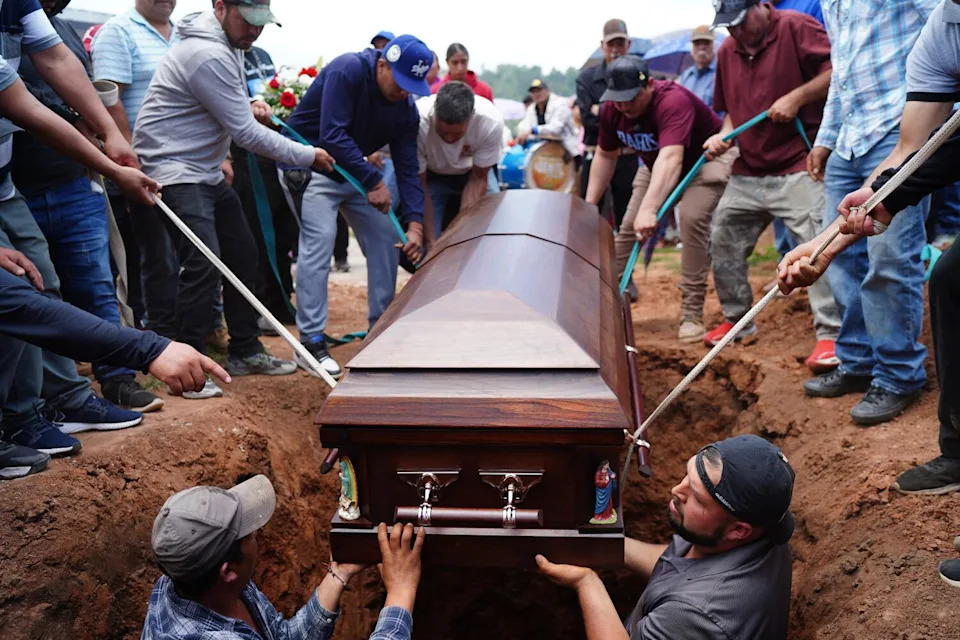 Men lower a casket into a grave.