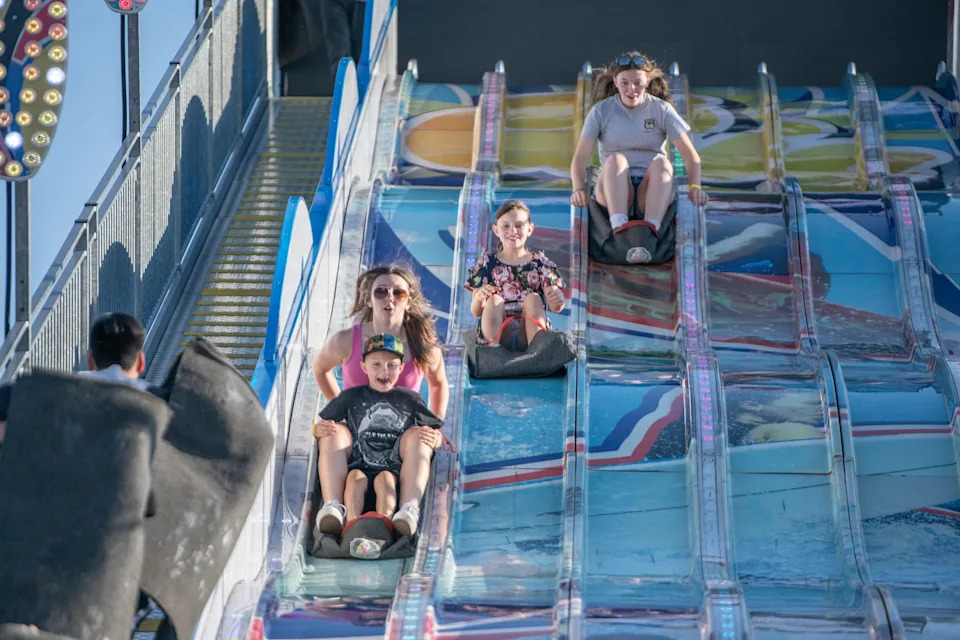 Youngsters smile as the fly down a super slide at the Colorado State Fair on Aug. 31, 2024.