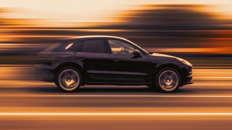 A black Porsche Macan speeds against a blurry background