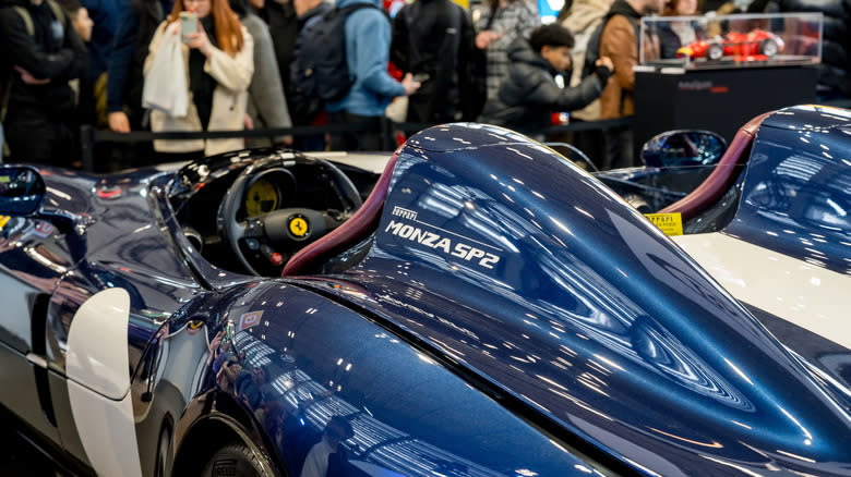 A view of a Blue Ferrari Monza SP2's left side and steering wheel with car show crowd in the background