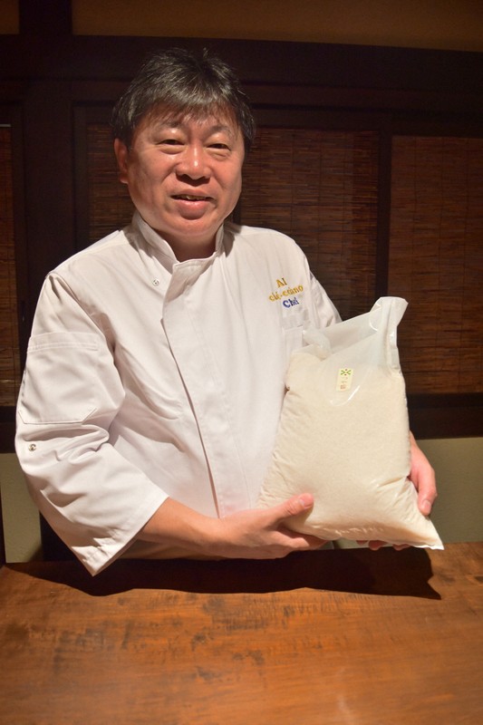 山形県産高級ブランド米「つや姫」を抱える奥田政行さん＝山形県鶴岡市で2025年7月30日午後7時33分、長南里香撮影