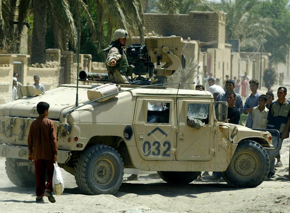 Un soldado del ejército estadounidense indicando a los aldeanos que se mantengan alejados de su vehículo durante una redada en busca de armas y sospechosos en la aldea de Shahravan, a 80 km al noreste de Bagdad, el 30 de junio de 2003, mientras su unidad, el pelotón 367 Scouts 4 I.D., participaba en la operación ‘Sidewinder’.