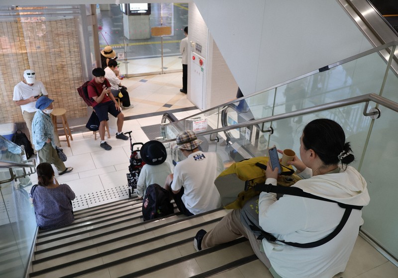 JR和歌山駅のドアが施錠され、駅ビルで運行再開を待つ利用者たち＝和歌山市で2025年7月30日午後1時18分、加藤敦久撮影