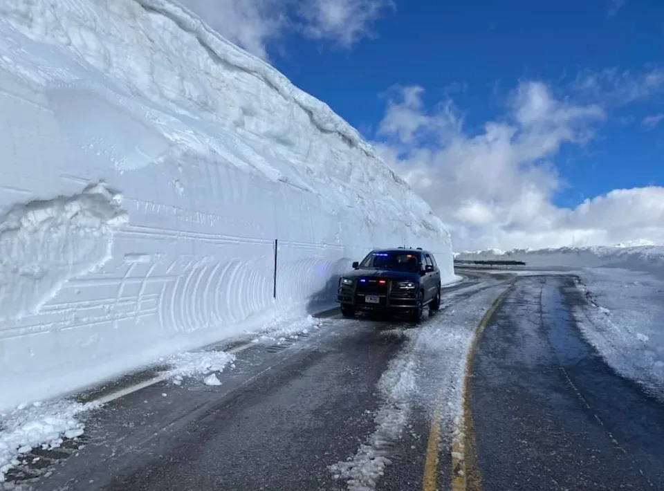 Police SUV drives past tall snowbanks along a cleared mountain road