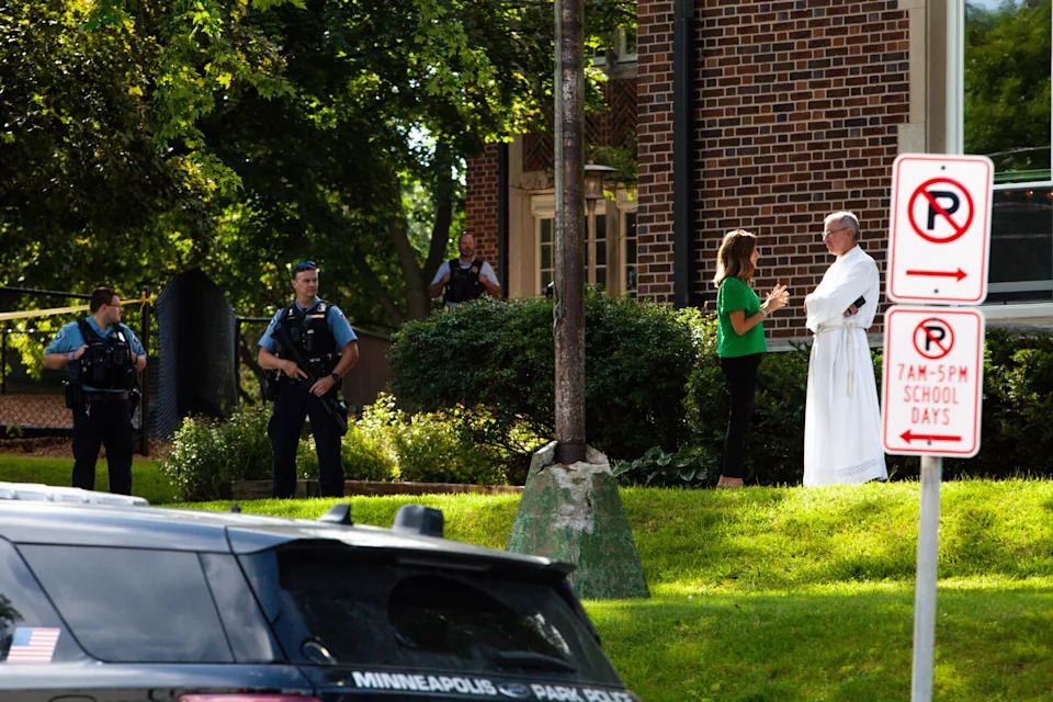 A woman talks to a clergy member as police stand guard at Annunciation School after a man killed two children and injured several others Wednesday, Aug. 27, 2025 in Minneapolis. (Photo by Nicole Neri/Minnesota Reformer)