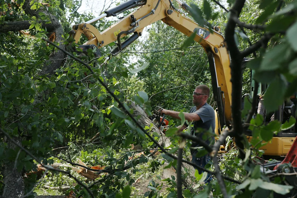 Hudson resident Doug Klarenbeek helps clean up tree debris in the town on Tuesday, July 29, 2025 after severe weather moved through the area Monday evening. The system damaged trees, homes and other structures. (Makenzie Huber/South Dakota Searchlight)