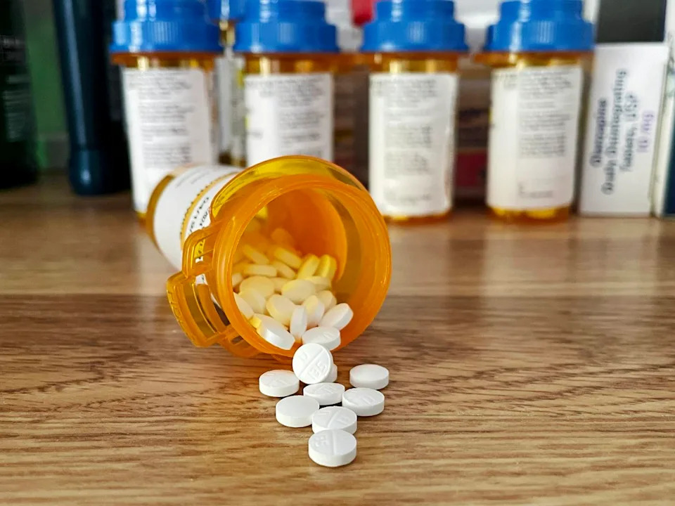 Antidepressants – white pills spilling out of a pill bottle onto wooden table