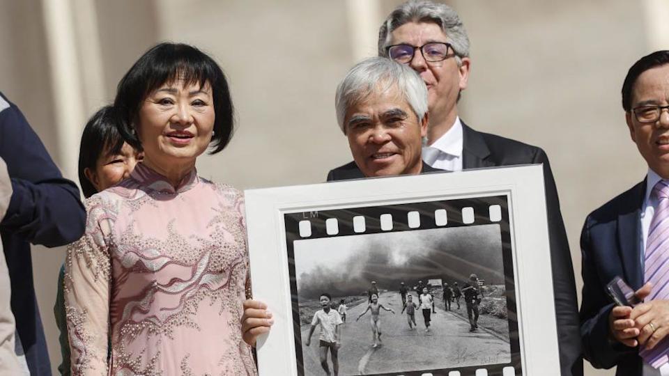 Nick Ut junto a Kim Phuc. El fotógrafo muestra la icónica foto de la guerra de Vietnam mientras esperan reunirse con el papa Francisco al final de su audiencia general semanal en la Plaza de San Pedro, Ciudad del Vaticano, el 11 de mayo de 2022.