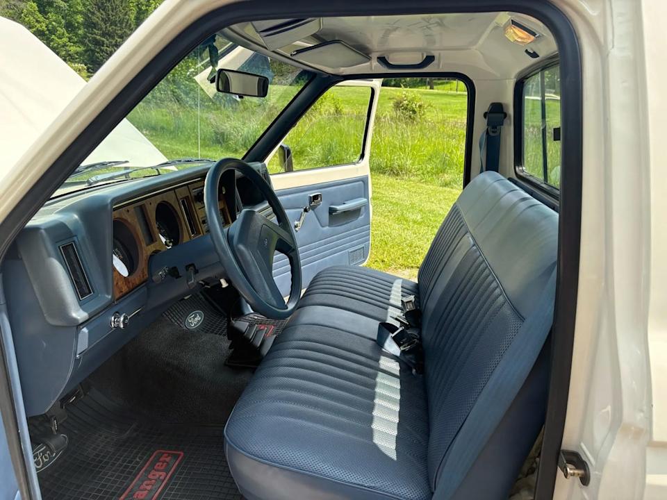 interior view from driver side showing blue bench seat, steering wheel, and dashboard.