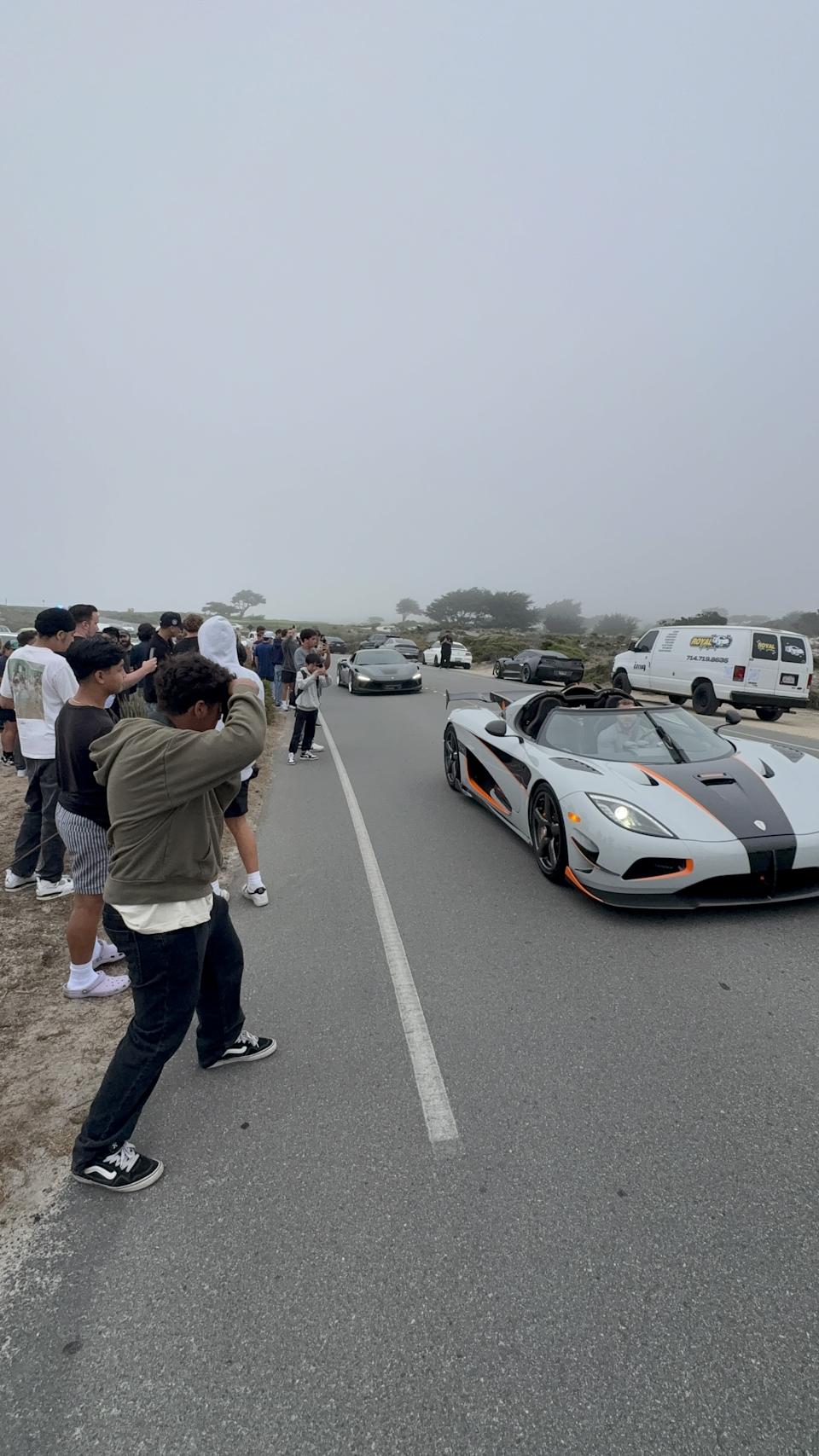 Crowds photographing Koenigseggs and Ferraris on the road
