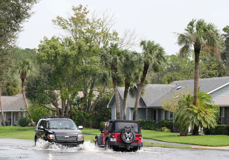 Vehicles with enough clearance drive through flooded streets in Pelican Bay in Daytona Beach after heavy rains from Hurricane Milton filled the canals and roadways, Thursday, Oct. 10, 2024.