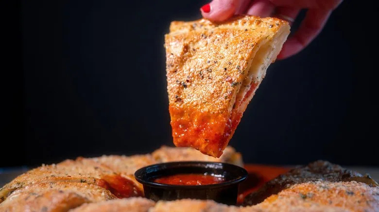 Piece of Mazzio's calzone ring dipped in sauce
